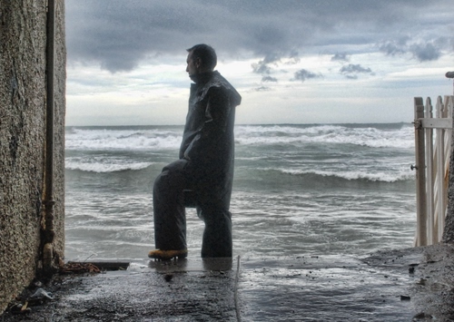 Immagine con mare, uomo, onde, acqua, nuvole, staccionata, cielo, muro, pioggia, inverno, maltempo, pescatore, schiuma